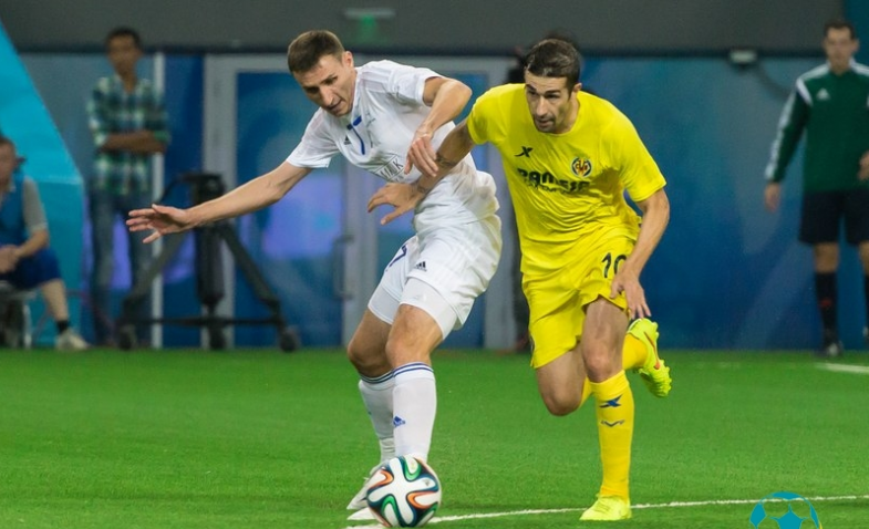 Дмитрий Шомко ведет борьбу за мяч с полузащитником испанцев Кани